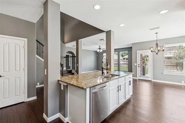 a hall with kitchen island white cabinets and wooden floor