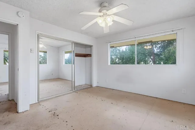 an empty room with a window and a ceiling fan