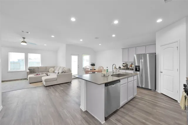 a living room with stainless steel appliances kitchen island granite countertop a couch and wooden floor