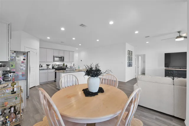 a kitchen with a dining table chairs and refrigerator
