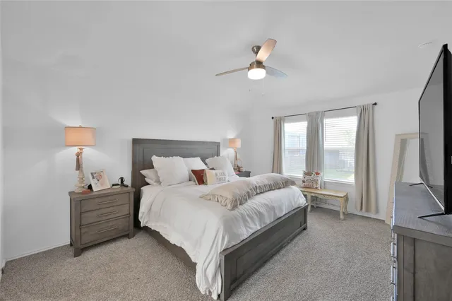 a bedroom with a bed flat screen tv and a large window