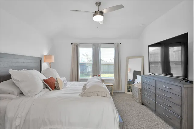 a bedroom with a large bed and a flat tv screen on dresser