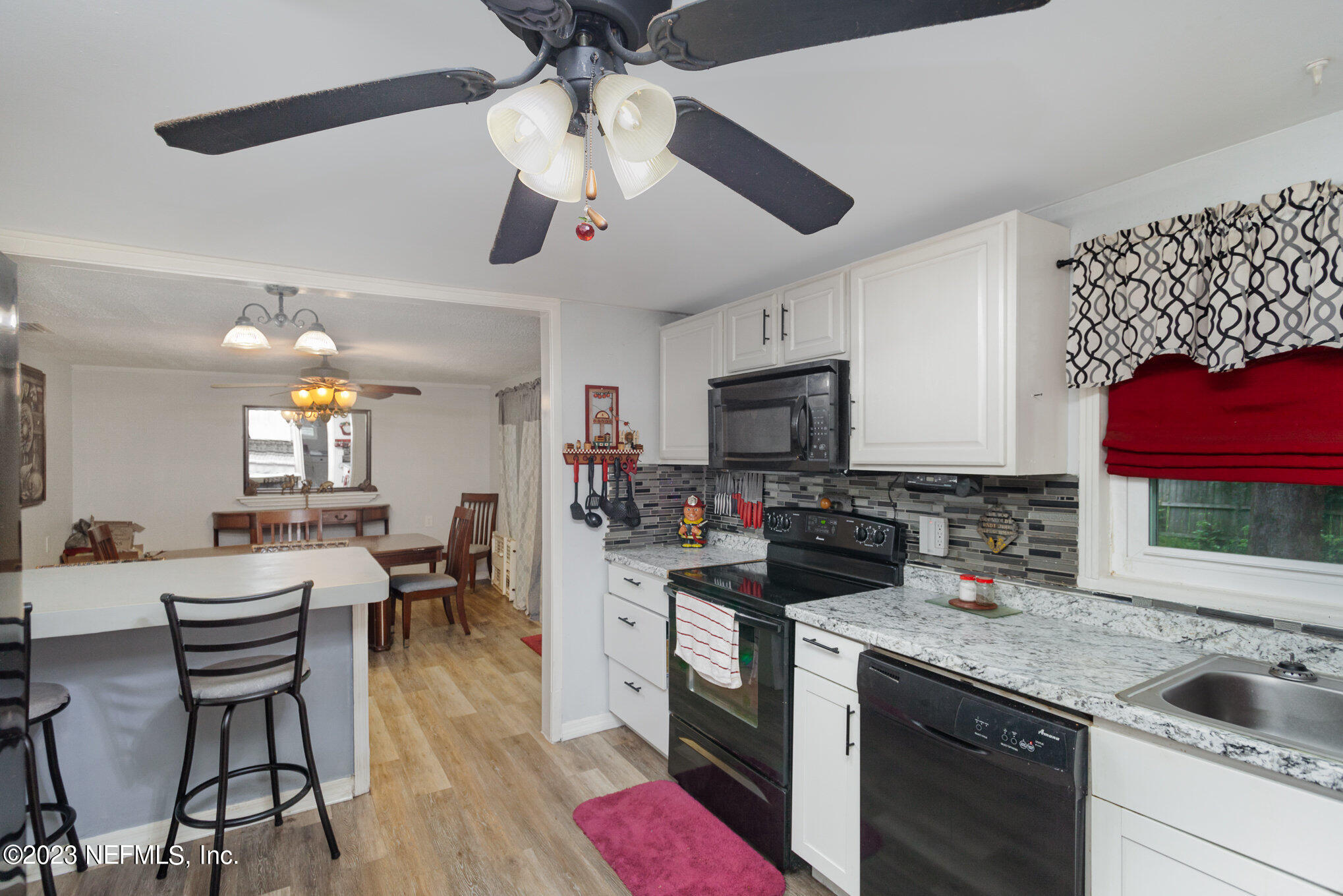 145 North Orange Street Starke, FL 32091 - Photo 10 of 26 a kitchen with a stove a sink dishwasher a dining table and chairs with wooden floor