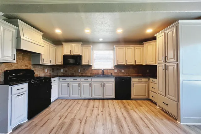 a kitchen with granite countertop a stove top oven sink and cabinets