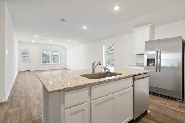 a large white kitchen with kitchen island a sink a stove a refrigerator and white cabinets with wooden floor