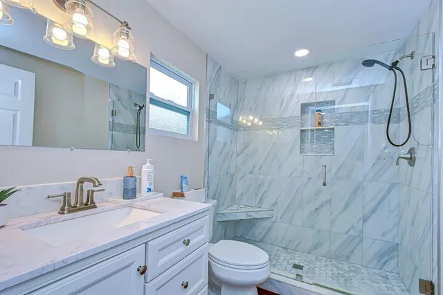 a bathroom with a granite countertop sink a toilet and shower
