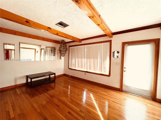a view of an empty room with window and wooden floor