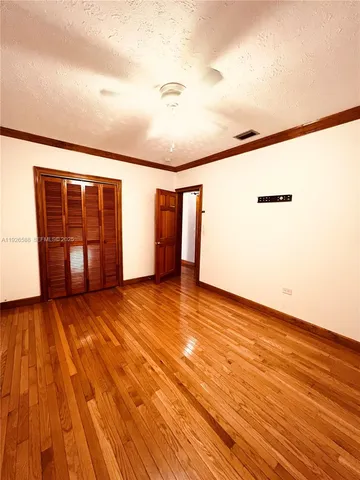 a view of an empty room with closet and wooden floor