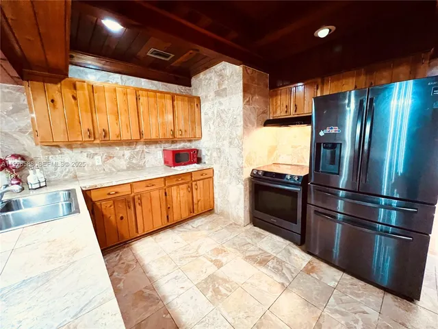 a kitchen with stainless steel appliances kitchen island granite countertop a refrigerator a sink dishwasher and a stove