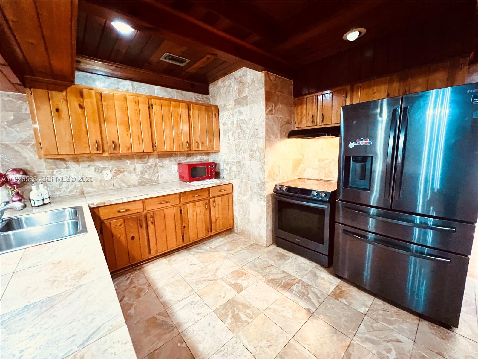 29625 Southwest 153rd Court Homestead, FL 33033 - Photo 8 of 17 a kitchen with stainless steel appliances kitchen island granite countertop a refrigerator a sink dishwasher and a stove