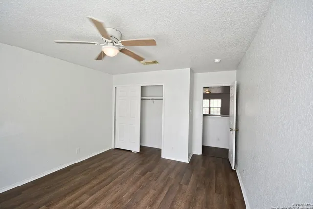 an empty room with wooden floor ceiling fan and windows
