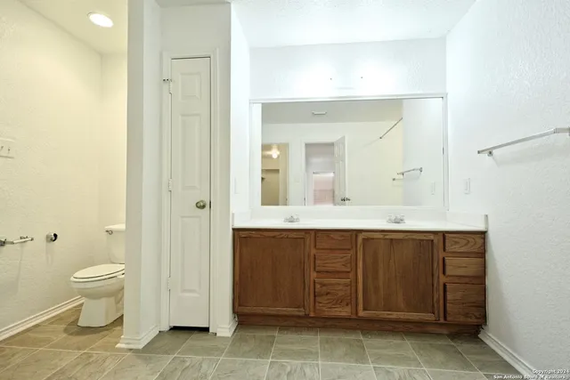 a spacious bathroom with a granite countertop sink a toilet and a mirror