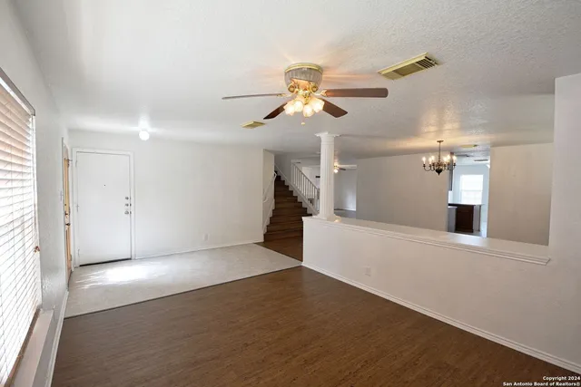 a view of a room with wooden floor and a ceiling fan