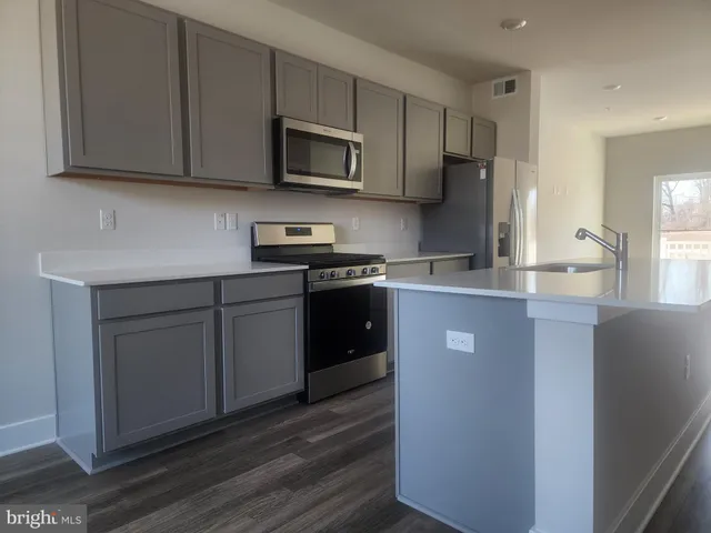 a kitchen with stainless steel appliances granite countertop a refrigerator a sink a stove a microwave and wooden cabinets