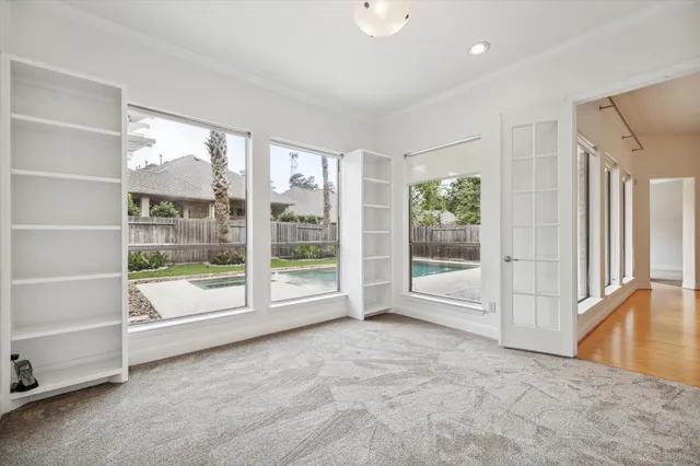 a view of an empty room with wooden floor and next to a window