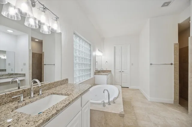 a bathroom with a granite countertop sink mirror and bathtub