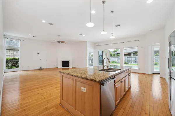 a kitchen with stainless steel appliances granite countertop a sink a stove and a wooden floors