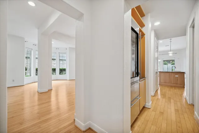 a view of a hallway with wooden floor windows and a bathroom