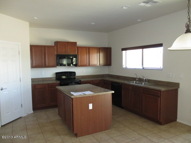 43500 West Magnolia Road Maricopa, AZ 85138 - Photo 4 of 35 a kitchen with stainless steel appliances granite countertop wooden cabinets a stove a sink and a refrigerator