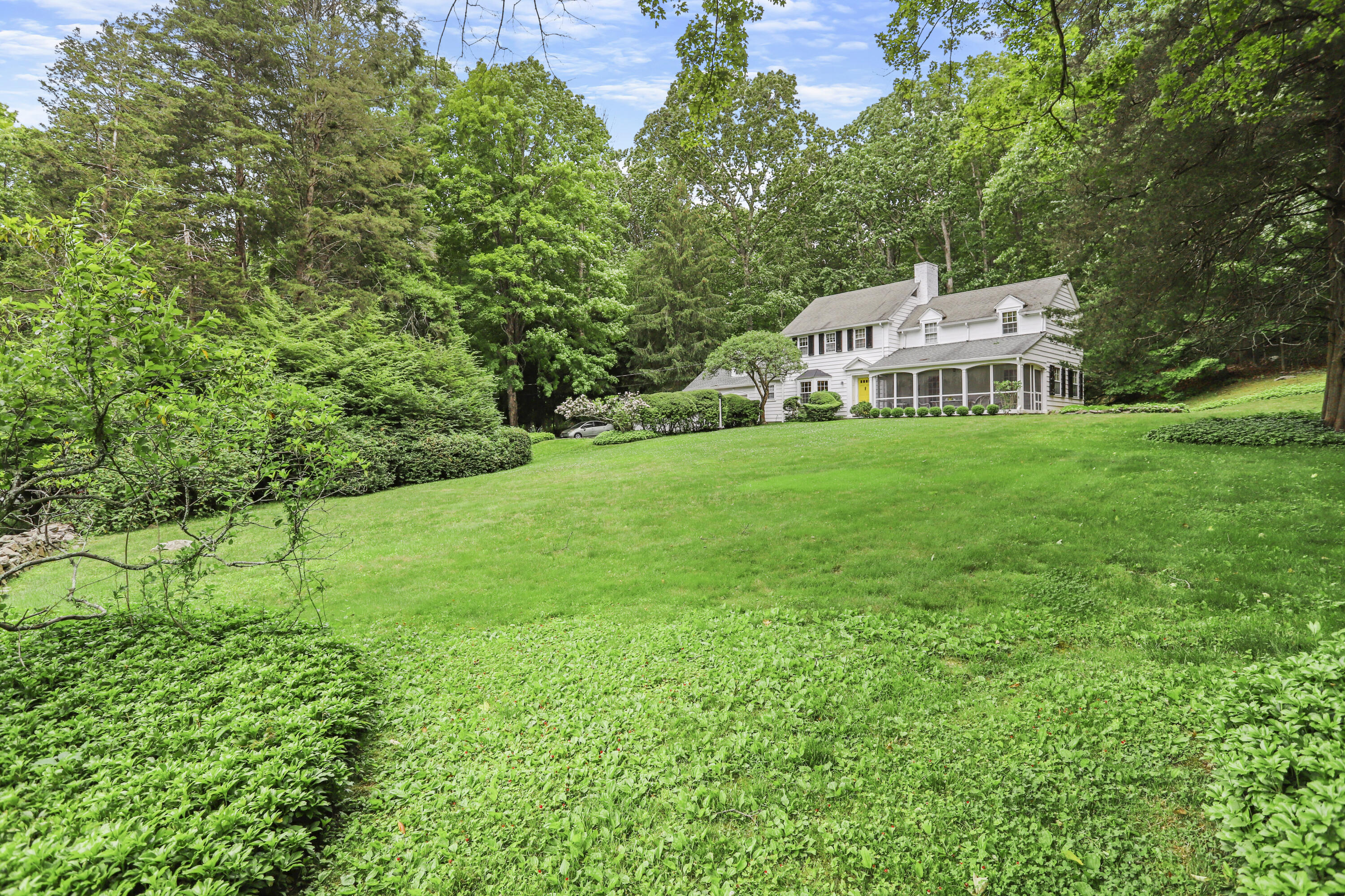 165 Colonial Road New Canaan, CT 06840 - Photo 2 of 37 a front view of a house with a garden