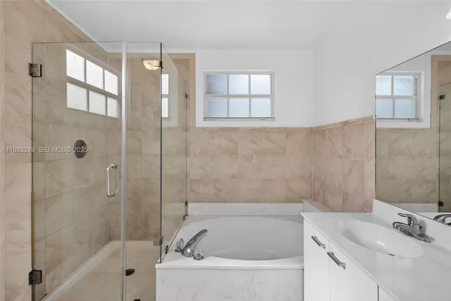 a white bath tub sitting next to a white sink and vanity