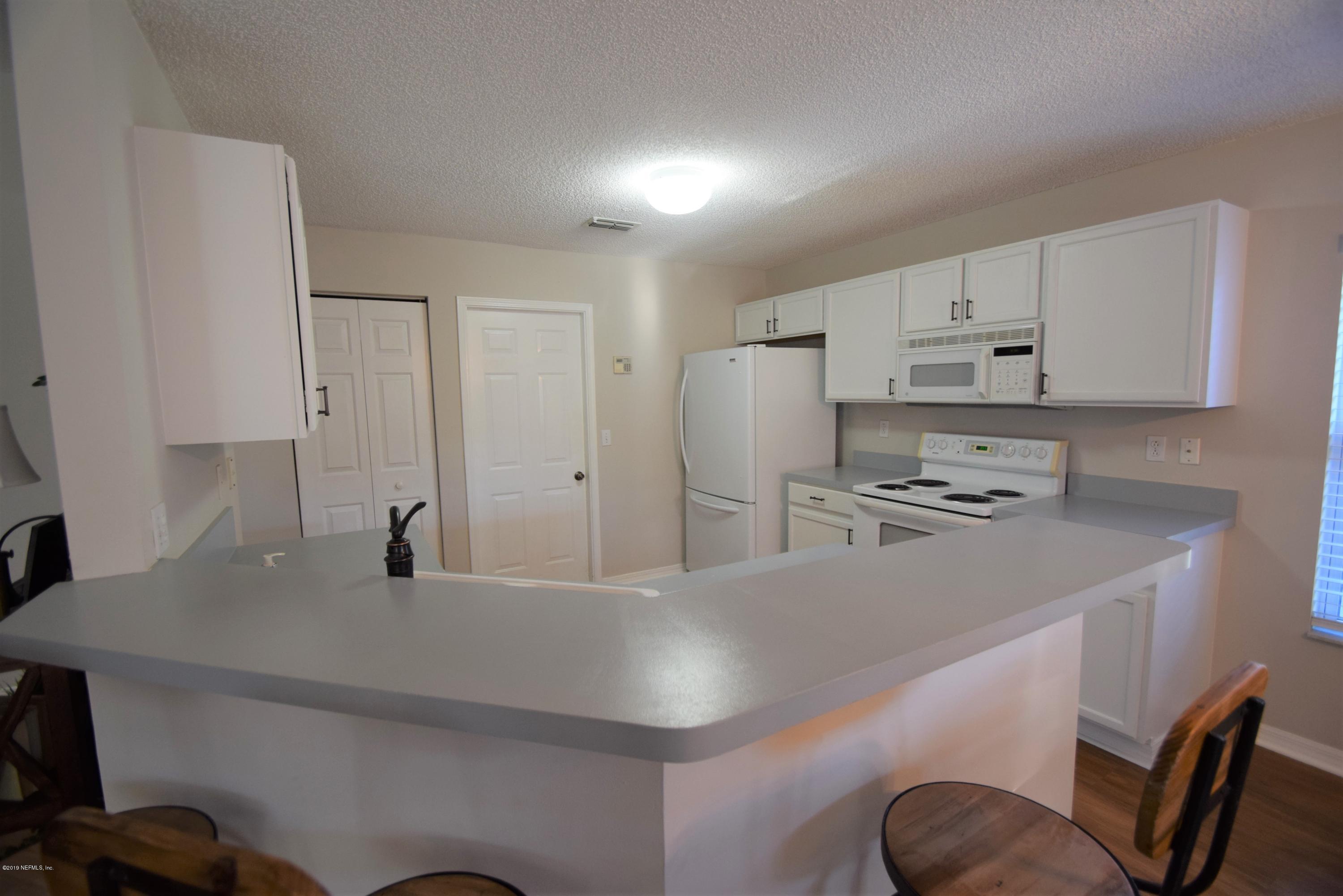 805 Sugarcane Avenue St. Augustine, FL 32095 - Photo 10 of 20 a kitchen with kitchen island a stove a sink a refrigerator and white cabinets with wooden floor
