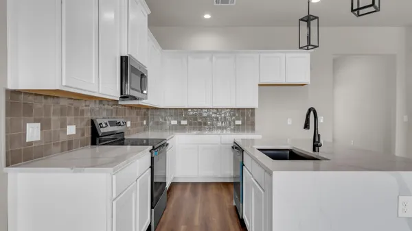 a kitchen with white cabinets sink and stove