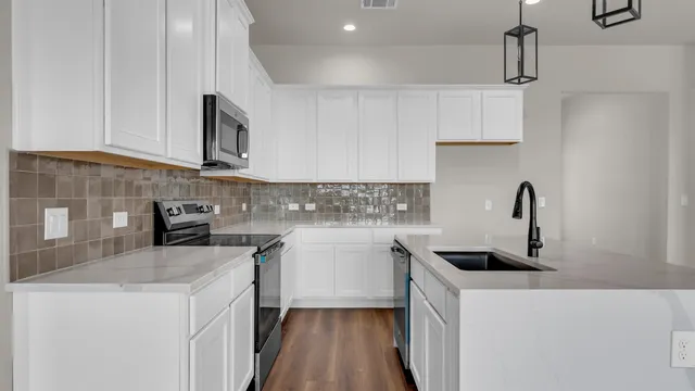 an empty room with wooden floor cabinet and windows