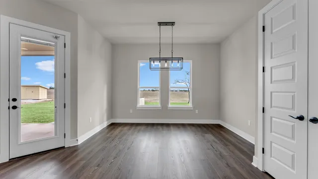 a view of an empty room with window and wooden floor