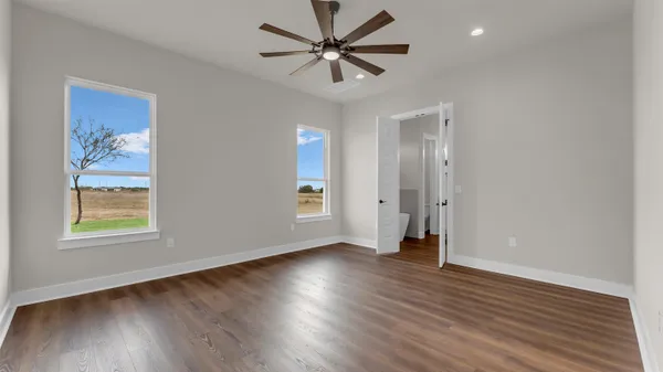 a view of an empty room with window and wooden floor