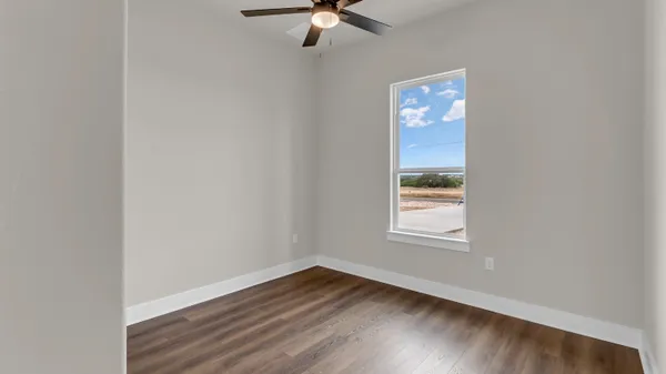 an empty room with wooden floor fan and windows