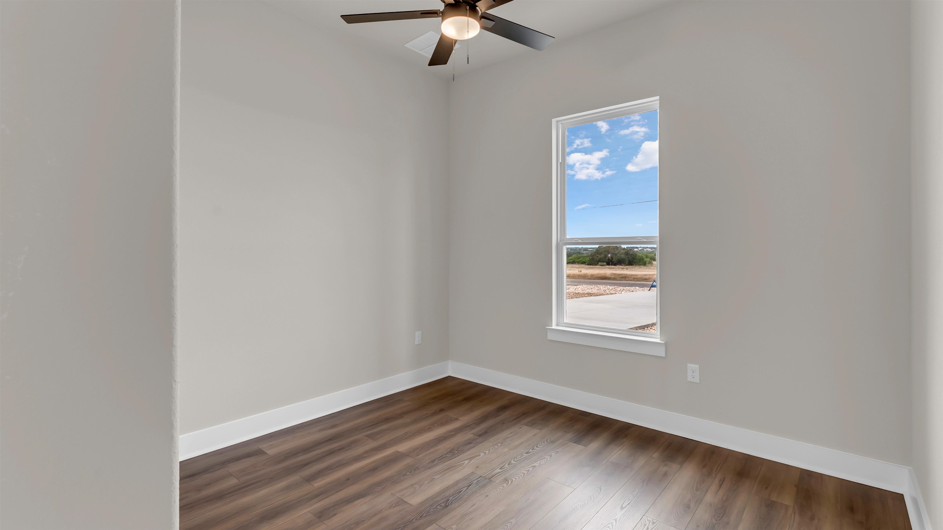 379 Prarie Point Road Bertram, TX 78605 - Photo 4 of 30 an empty room with wooden floor fan and windows