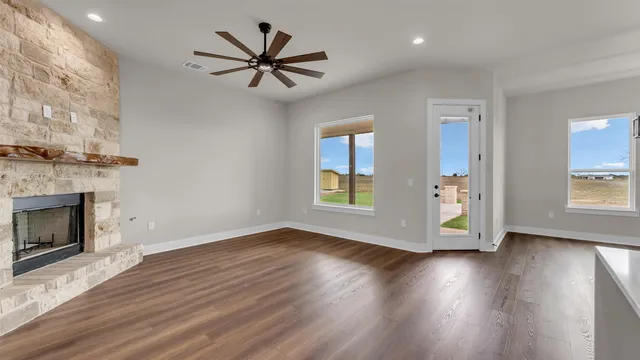 a view of a livingroom with wooden floor a ceiling fan and a fireplace