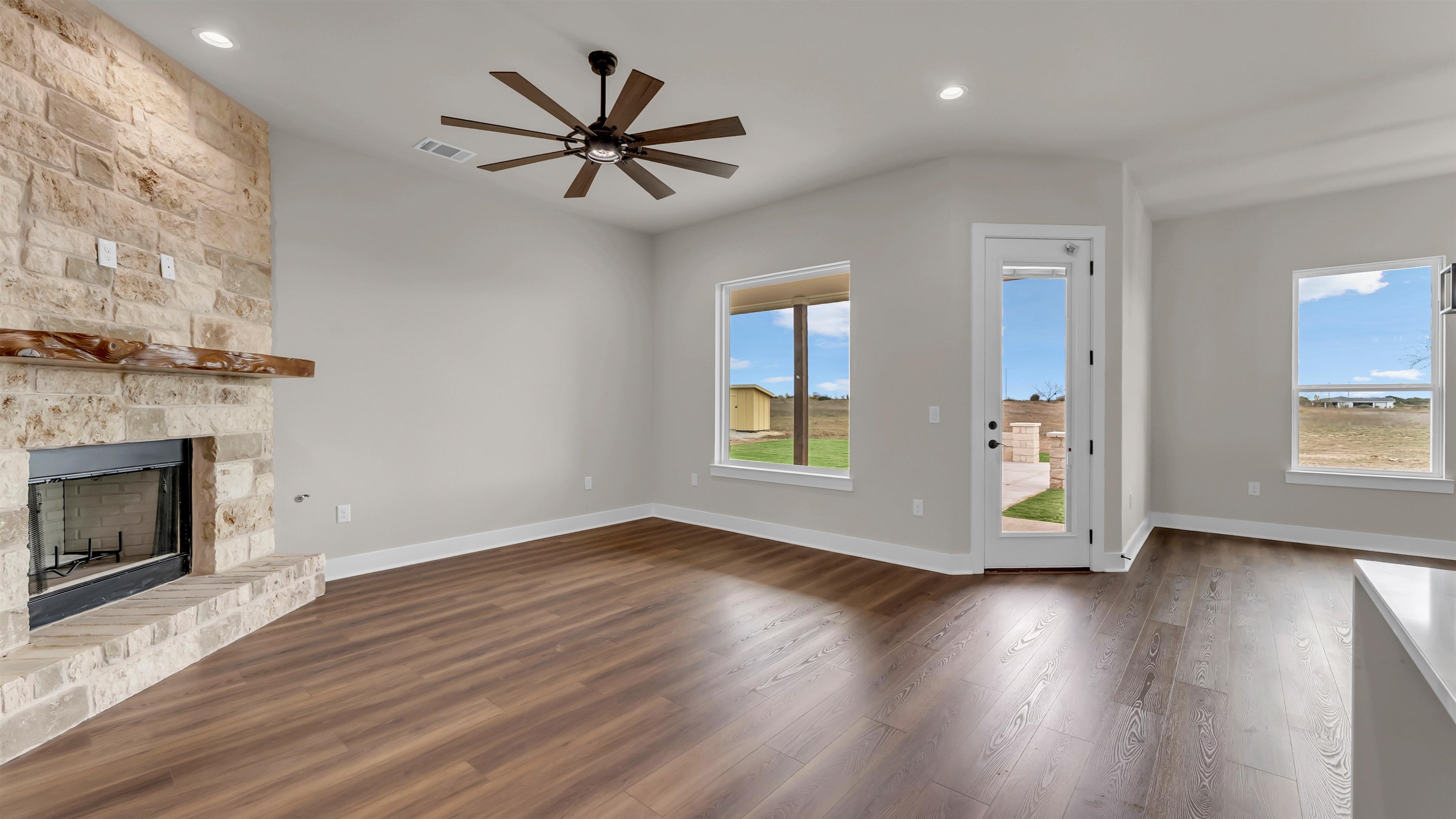 379 Prarie Point Road Bertram, TX 78605 - Photo 6 of 30 a view of a livingroom with wooden floor a ceiling fan and a fireplace