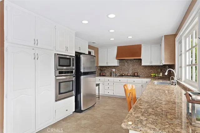 a kitchen with stainless steel appliances granite countertop a refrigerator sink stove microwave and cabinets