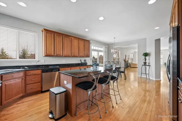 a kitchen with stainless steel appliances granite countertop a table chairs sink and wooden floor