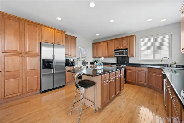 a kitchen with stainless steel appliances granite countertop a refrigerator a sink dishwasher a stove with wooden cabinets and a granite counter top