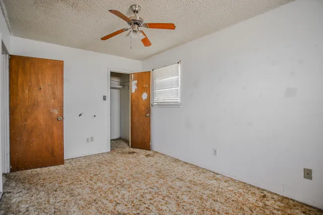 a view of a room with a ceiling fan and window