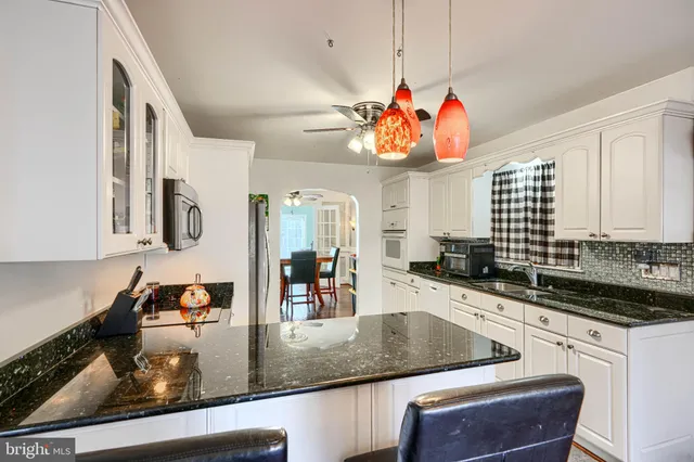 a kitchen with stainless steel appliances granite countertop a sink a stove and a wooden cabinets