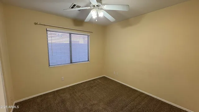 an empty room with a window and a ceiling fan