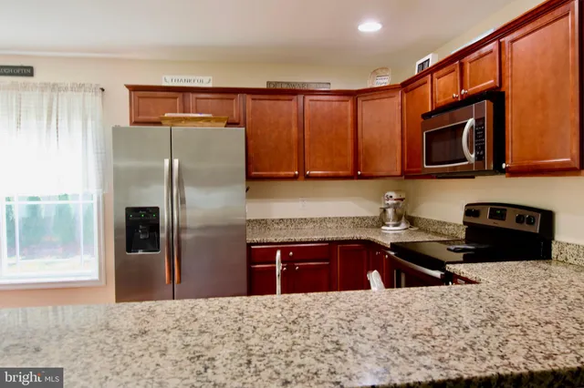 a kitchen with stainless steel appliances granite countertop a refrigerator a stove top oven a sink and dishwasher