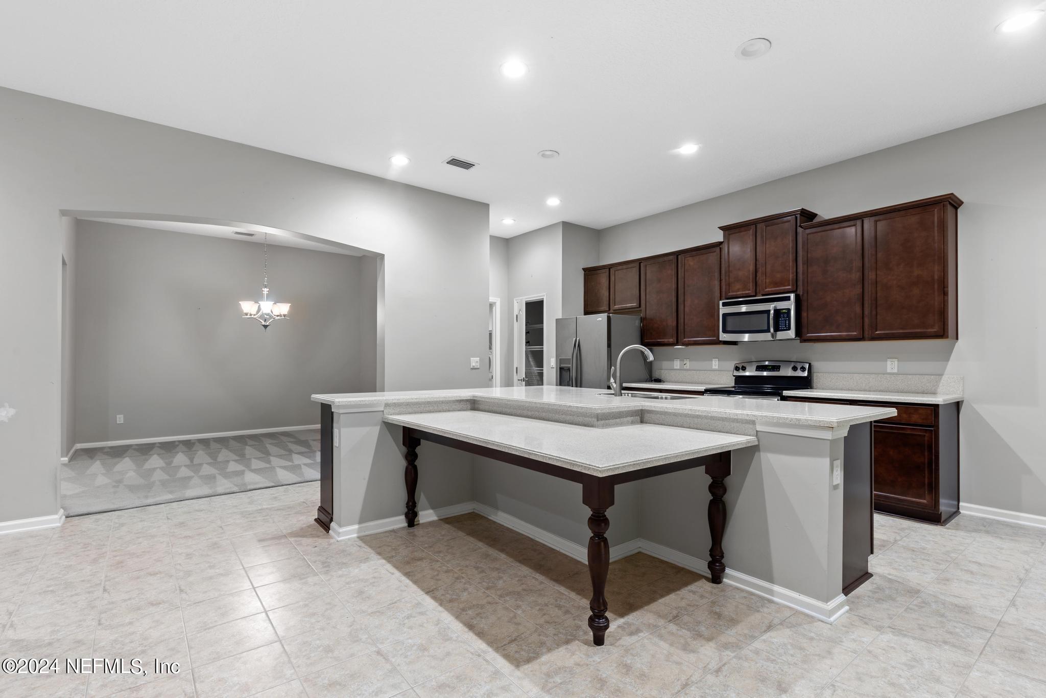 86192 Fortune Drive Yulee, FL 32097 - Photo 7 of 26 a kitchen with kitchen island a sink cabinets and wooden floor