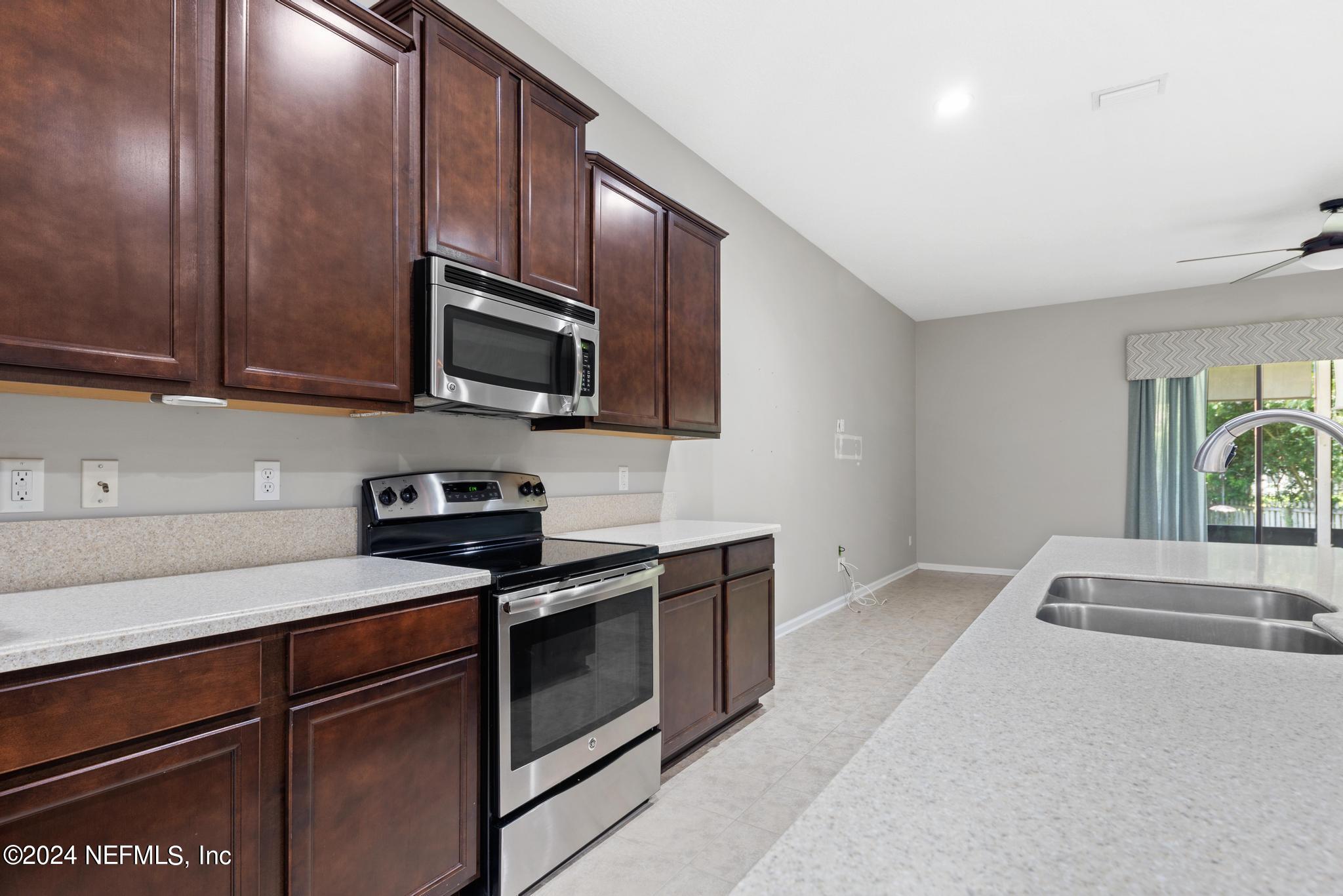 86192 Fortune Drive Yulee, FL 32097 - Photo 9 of 26 a kitchen with granite countertop wooden cabinets stainless steel appliances and a sink