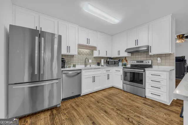 a kitchen with a refrigerator stove and white cabinets