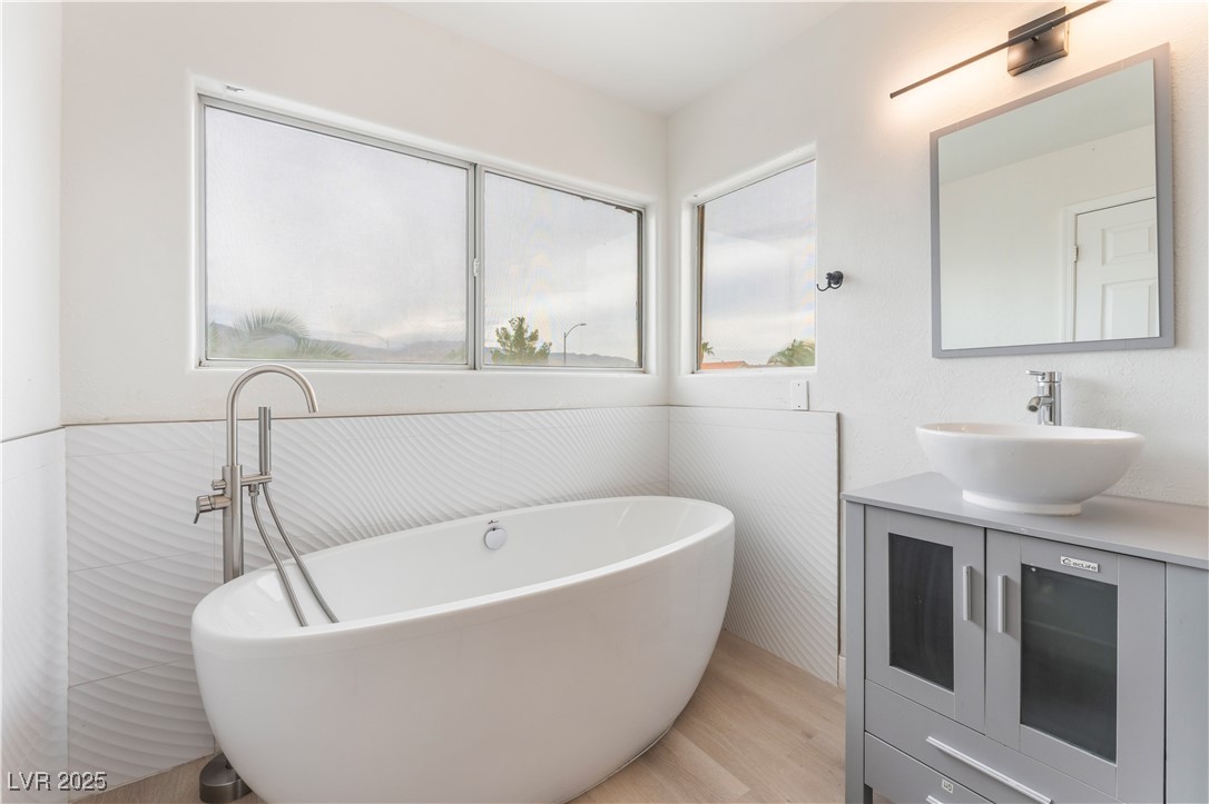 3695 Funston Way Las Vegas, NV 89129 - Photo 31 of 43 Full bathroom featuring vanity, a freestanding tub, and light wood-type flooring