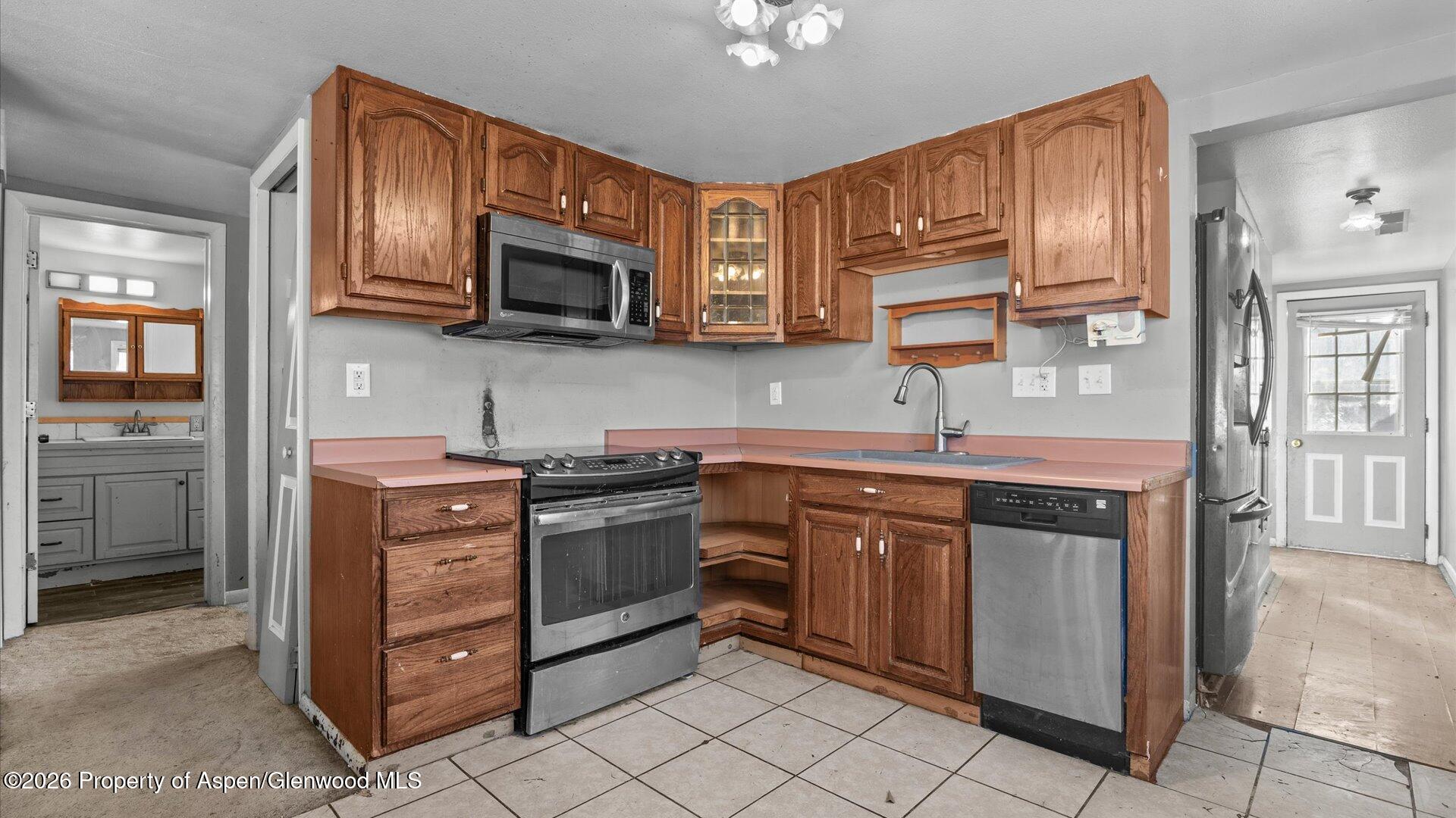 109 East 12th Street Rifle, CO 81650 - Photo 13 of 31 a kitchen with stainless steel appliances granite countertop a stove top oven a sink dishwasher and a refrigerator with wooden cabinets
