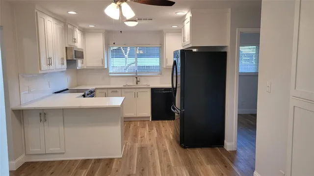 a kitchen with a sink a refrigerator a stove and black cabinets