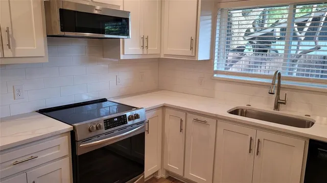 a kitchen with white cabinets and a stove top oven