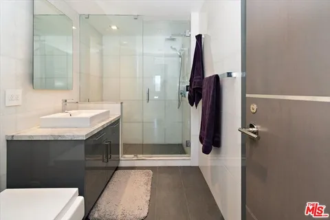 a bathroom with a sink vanity granite tub shower and mirror