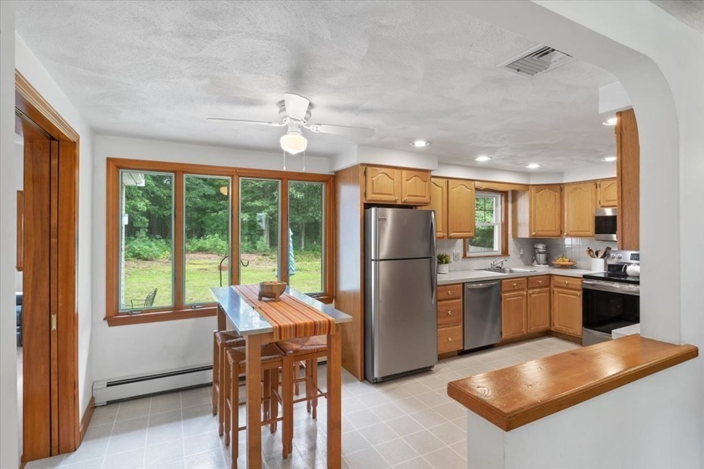 23 Old Post Road East Walpole, MA 02032 - Photo 7 of 27 a kitchen with a refrigerator a stove and a dining table